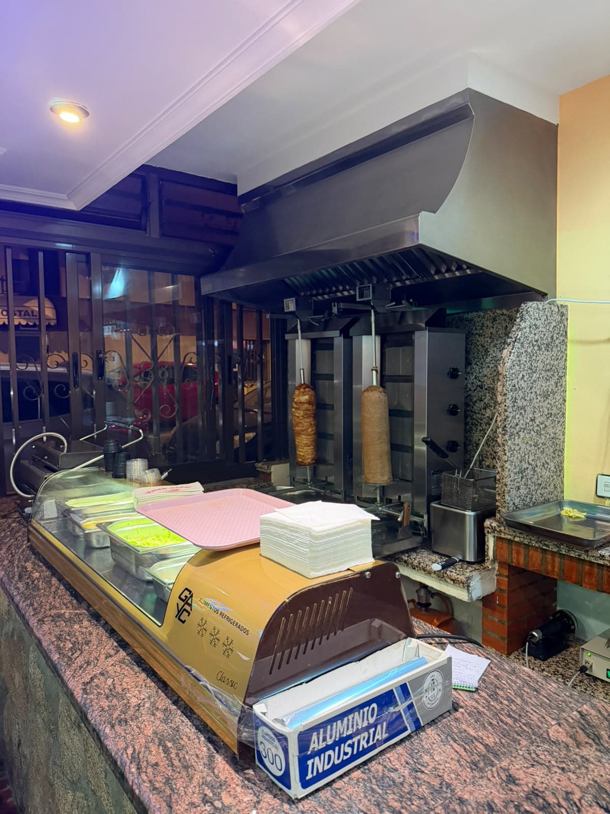 Los dos asadores de döner girando detrás de la barra del local