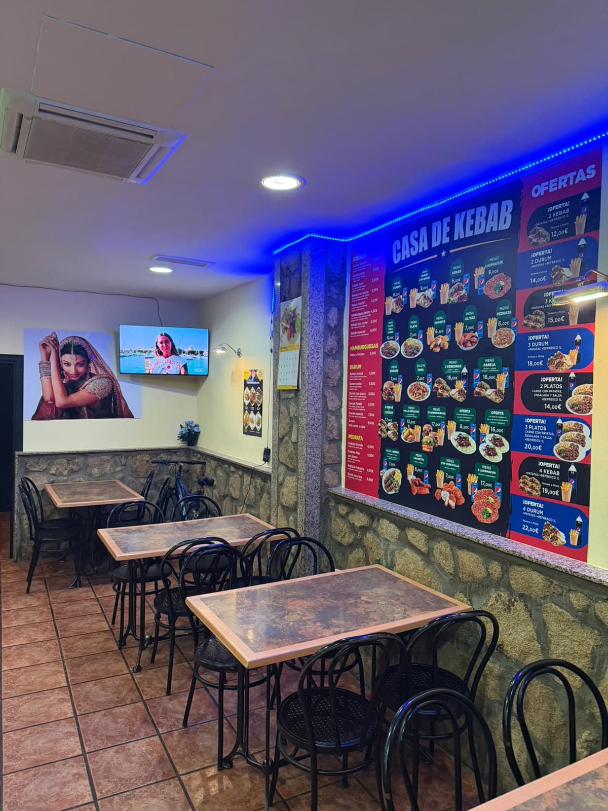 Comedor con mesas y el panel de ofertas iluminado en la pared