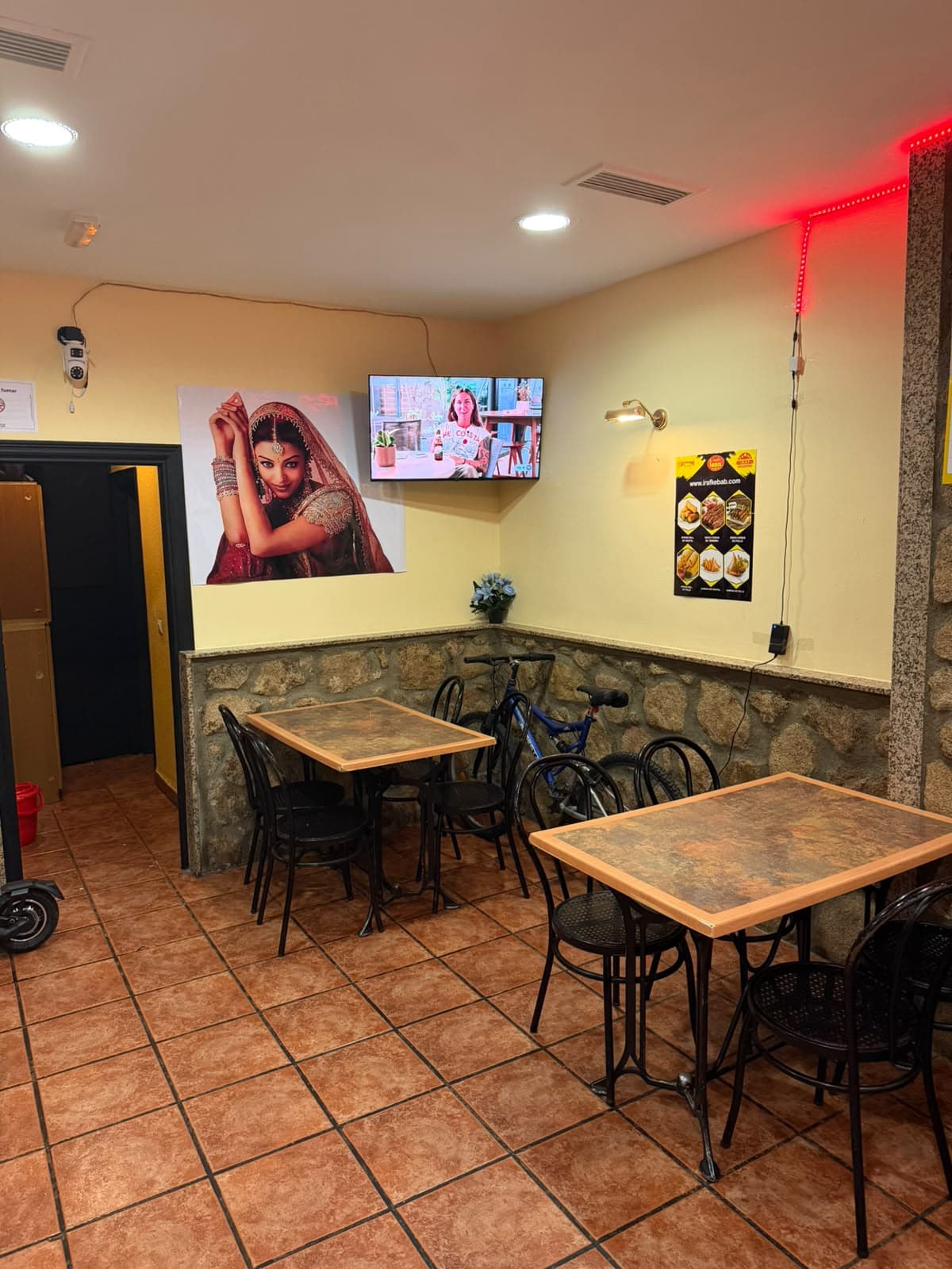 Zona de mesas del comedor con televisión y luz cálida