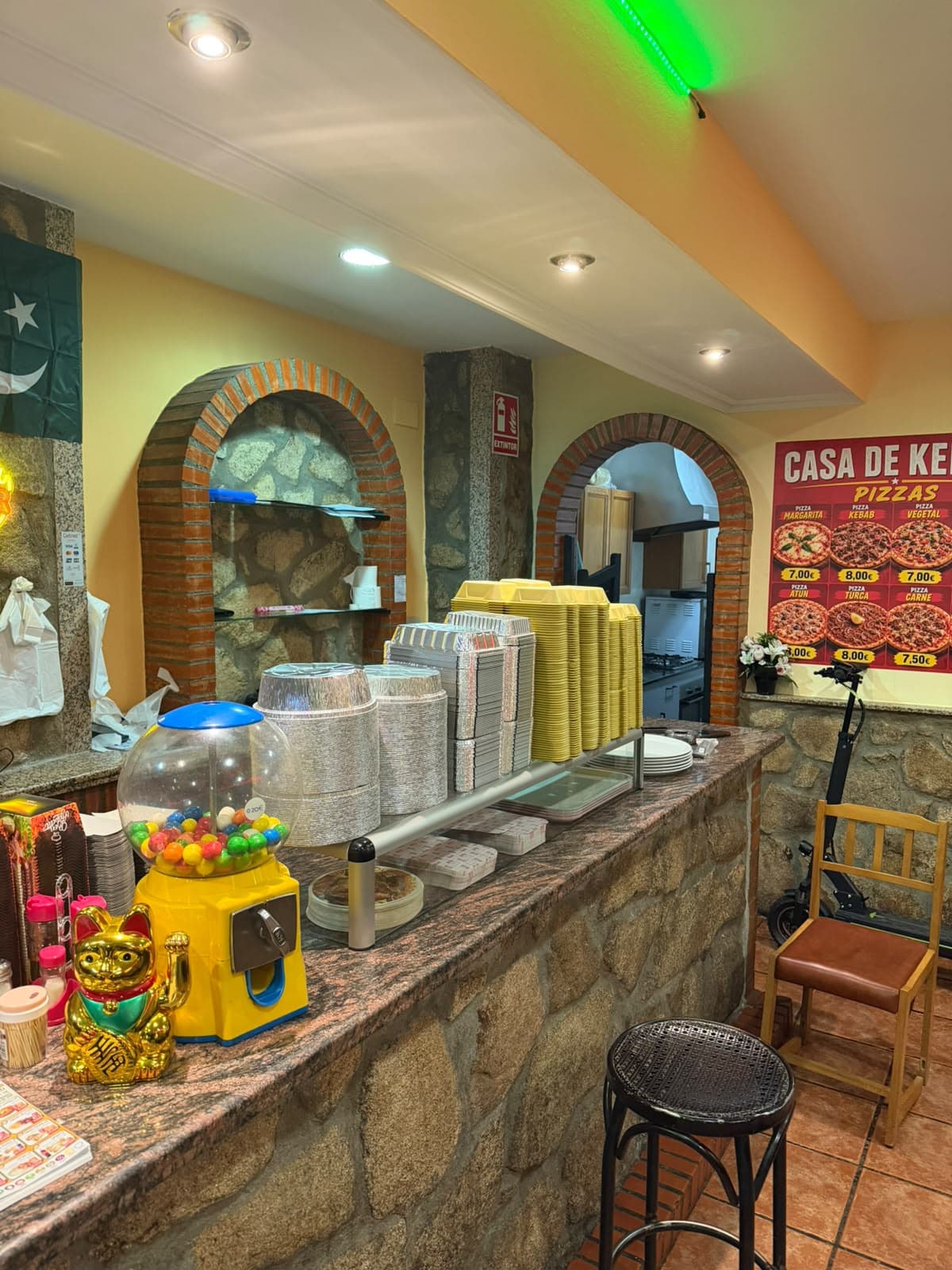 Mostrador del local con los arcos de ladrillo y el cartel de pizzas